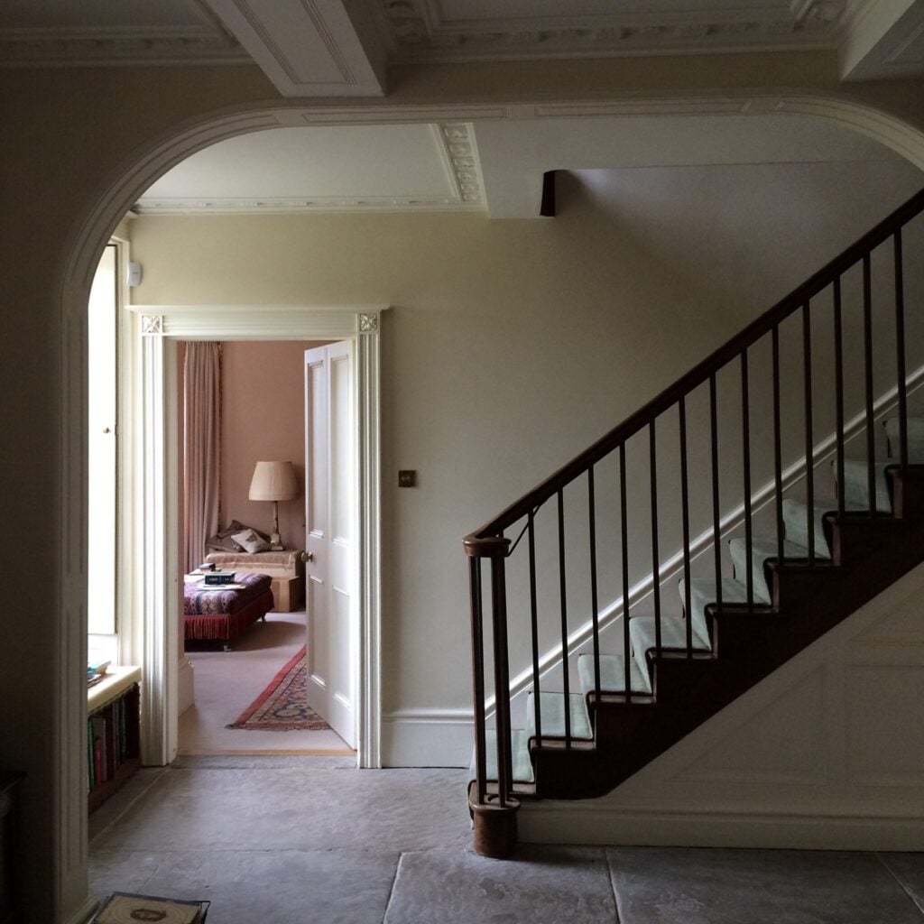 Hallway in shade showing walls painted in Stone White and staircase.