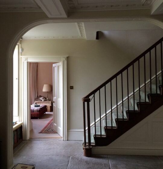 Hallway in shade showing walls painted in Stone White and staircase.