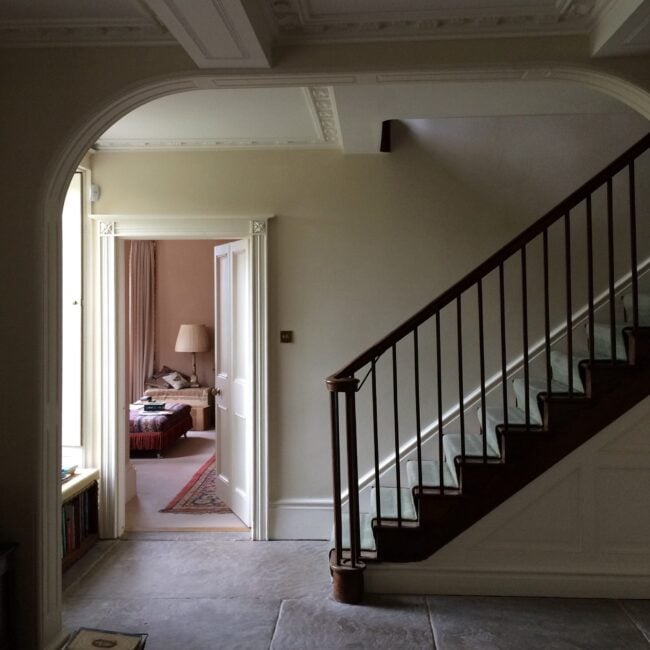 Hallway in shade showing walls painted in Stone White and staircase.