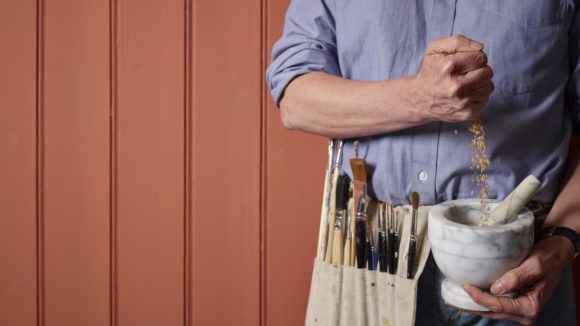 A man showing how natural paints are made with pestle and mortar