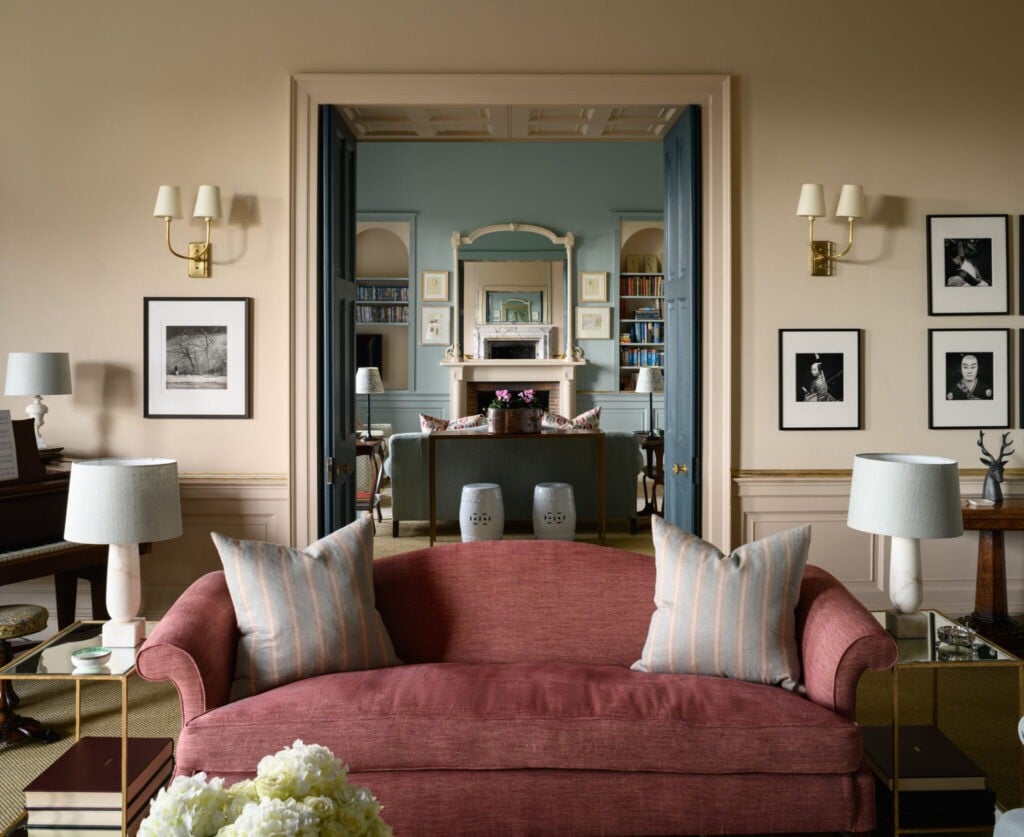 Lilac pink living room with a dusky pink sofa, striped cushions and a ethereal blue painted room beyond